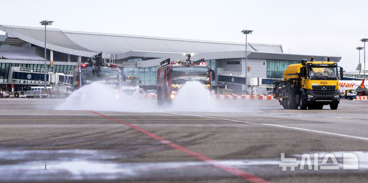 [서울=뉴시스] 김선웅 기자 = 12일 서울 강서구 김포국제공항 국내선 이동지역에서 한국공항공사 관계자들이 소방차를 이용해 폭염 대비 계류장 살수작업을 하고 있다. 살수작업은 활주로 등 이동지역 포장면의 표면온도가 60도 이상일 경우 물을 살포해 온도를 약 10도 가량 낮추어 포장 손상 위험을 줄이고 항공기 운항 안전성을 높이는 효과가 있다. 한국공항공사는 폭염경보가 발령될 경우 항공기 이동지역 포장면의 온도를 하루 세 차례 측정해 살수작업 여부를 결정한다. 2025.08.12. mangusta@newsis.com