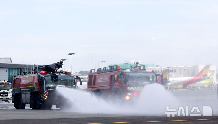 [서울=뉴시스] 김선웅 기자 = 12일 서울 강서구 김포국제공항 국내선 이동지역에서 한국공항공사 관계자들이 소방차를 이용해 폭염 대비 계류장 살수작업을 하고 있다. 살수작업은 활주로 등 이동지역 포장면의 표면온도가 60도 이상일 경우 물을 살포해 온도를 약 10도 가량 낮추어 포장 손상 위험을 줄이고 항공기 운항 안전성을 높이는 효과가 있다. 한국공항공사는 폭염경보가 발령될 경우 항공기 이동지역 포장면의 온도를 하루 세 차례 측정해 살수작업 여부를 결정한다. (공동취재) 2025.08.12. photo@newsis.com