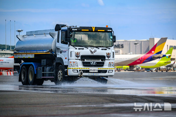 [서울=뉴시스] 김선웅 기자 = 12일 서울 강서구 김포국제공항 국내선 이동지역에서 한국공항공사 관계자들이 살수차를 이용해 폭염 대비 계류장 살수작업을 하고 있다. 살수작업은 활주로 등 이동지역 포장면의 표면온도가 60도 이상일 경우 물을 살포해 온도를 약 10도 가량 낮추어 포장 손상 위험을 줄이고 항공기 운항 안전성을 높이는 효과가 있다. 한국공항공사는 폭염경보가 발령될 경우 항공기 이동지역 포장면의 온도를 하루 세 차례 측정해 살수작업 여부를 결정한다. (공동취재) 2025.08.12. photo@newsis.com