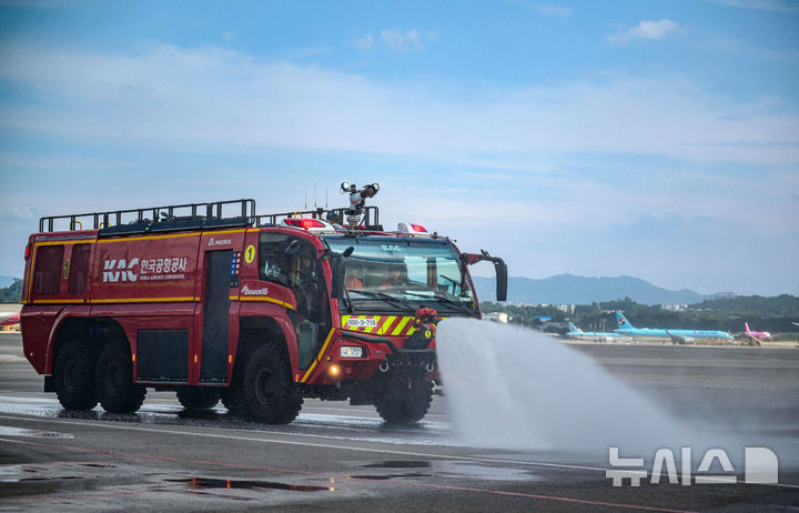 [서울=뉴시스] 김선웅 기자 = 12일 서울 강서구 김포국제공항 국내선 이동지역에서 한국공항공사 관계자들이 소방차를 이용해 폭염 대비 계류장 살수작업을 하고 있다. 살수작업은 활주로 등 이동지역 포장면의 표면온도가 60도 이상일 경우 물을 살포해 온도를 약 10도 가량 낮추어 포장 손상 위험을 줄이고 항공기 운항 안전성을 높이는 효과가 있다. 한국공항공사는 폭염경보가 발령될 경우 항공기 이동지역 포장면의 온도를 하루 세 차례 측정해 살수작업 여부를 결정한다. (공동취재) 2025.08.12. photo@newsis.com