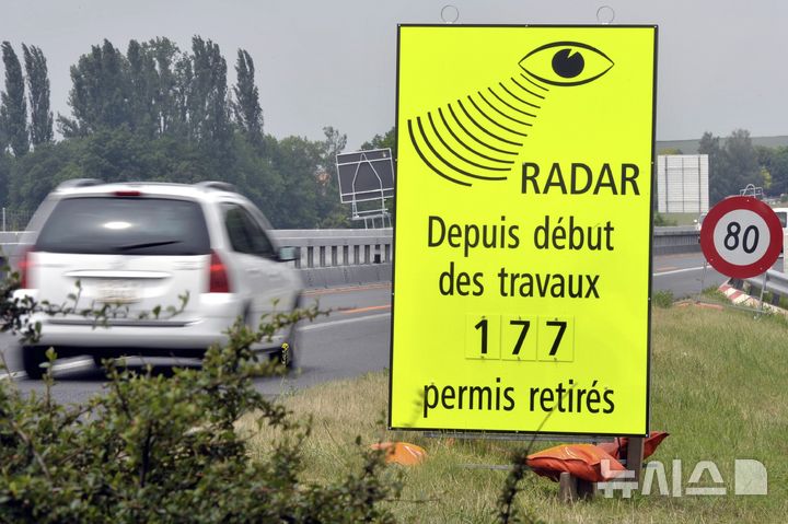 FILE - A vehicle passes in front of a sign of the Vaud Cantonal Police indicating the number of driving licences withdrawn for speeding in the construction zone on the A1 motorway between Lausanne and Yverdon, Switzerland, Tuesday, June 15, 2010. (Dominic Favre/Keystone via AP, file)