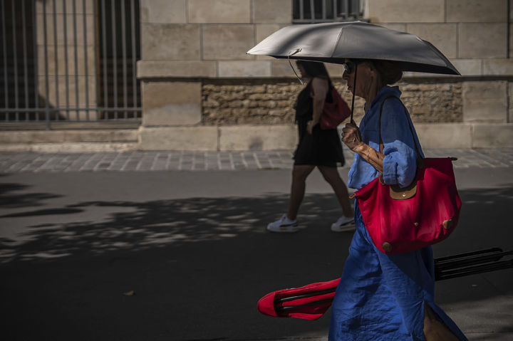 [파리=AP/뉴시스] 12일(현지 시간) 프랑스 파리에서 시민이 양산을 쓴 채 이동하고 있다. 2025.08.13.