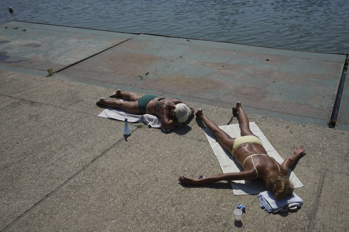 [세르비아=AP/뉴시스] 12일(현지 시간) 세르비아 베오그라드 아다 시간리야 호수 인근에서 시민들이 일광욕을 하고 있다. 2025.08.13.