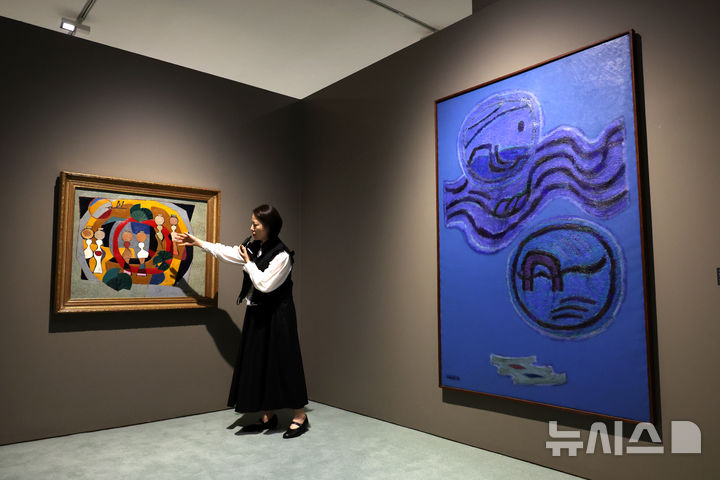 [서울=뉴시스] 박진희 기자 = 김미금 국립현대미술관 학예연구사가 13일 서울 중구 국립현대미술관 덕수궁에서 광복 80주년 기념전 '향수(鄕愁), 고향을 그리다' 전시작인 김환기 작가의 '섬 스케치'(왼쪽)와 '운월'을 설명하고 있다. 2025.08.13. pak7130@newsis.com