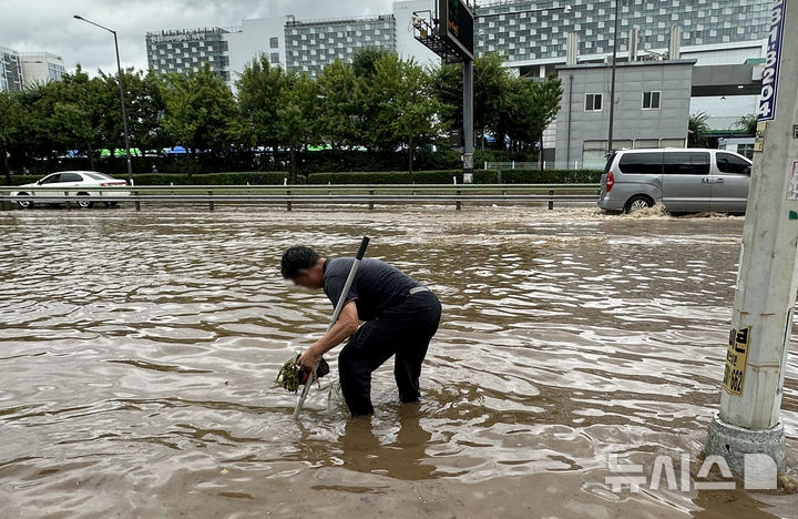 [고양=뉴시스] 홍효식 기자 = 서울을 비롯한 수도권에 호우주의보가 내린 13일 경기 고양시 통일로에서 한 시민이 빗물받이에 쌓인 쓰레기를 정리하고 있다. 2025.08.13. yesphoto@newsis.com
