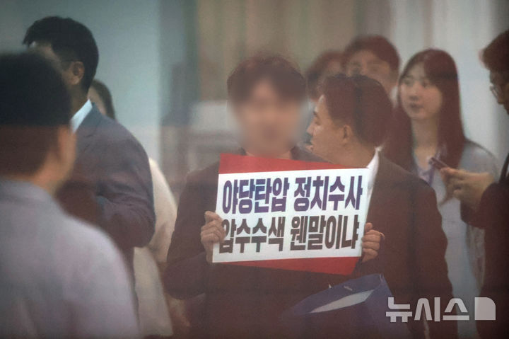 [서울=뉴시스] 김금보 기자 = 김건희 특검팀이 국민의힘 당사에 대한 압수수색에 나선 13일 서울 여의도 국민의힘 중앙당사에서 당 관계자가 항의 피켓을 들고 있다. 2025.08.13. kgb@newsis.com