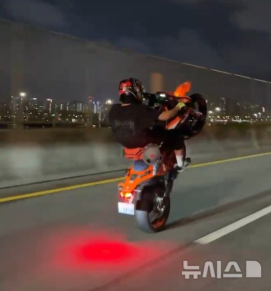 [서울=뉴시스]서울 성동경찰서는 성동구와 광진구 일대에서 야간 폭주행위를 한 일당 11명을 도로교통법 위반 혐의로 붙잡아 검찰에 송치할 예정이라고 14일 밝혔다. 사진은 성동경찰서가 검거한 폭주족 일당 중 한 명이 야간에 서울 시내 도로에서 앞바퀴를 들고 주행하는 모습.(사진=성동경찰서 제공)