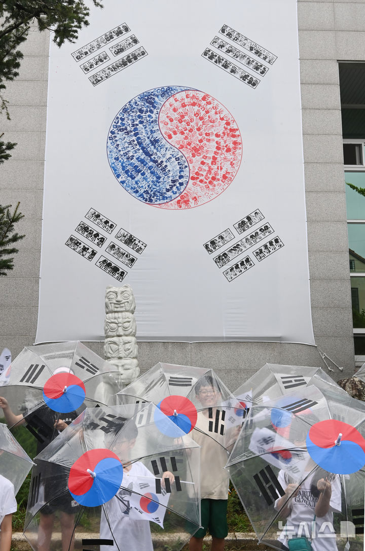 [수원=뉴시스] 김종택 기자 = 제80주년 광복절을 하루 앞둔 14일 경기 수원시 세류1동 행정복지센터에서 세류1동 새마을문고 '책먹는 아이들' 어린이들이 태극기 우산을 쓰고 만세삼창을 외치고 있다. 2025.08.14. jtk@newsis.com