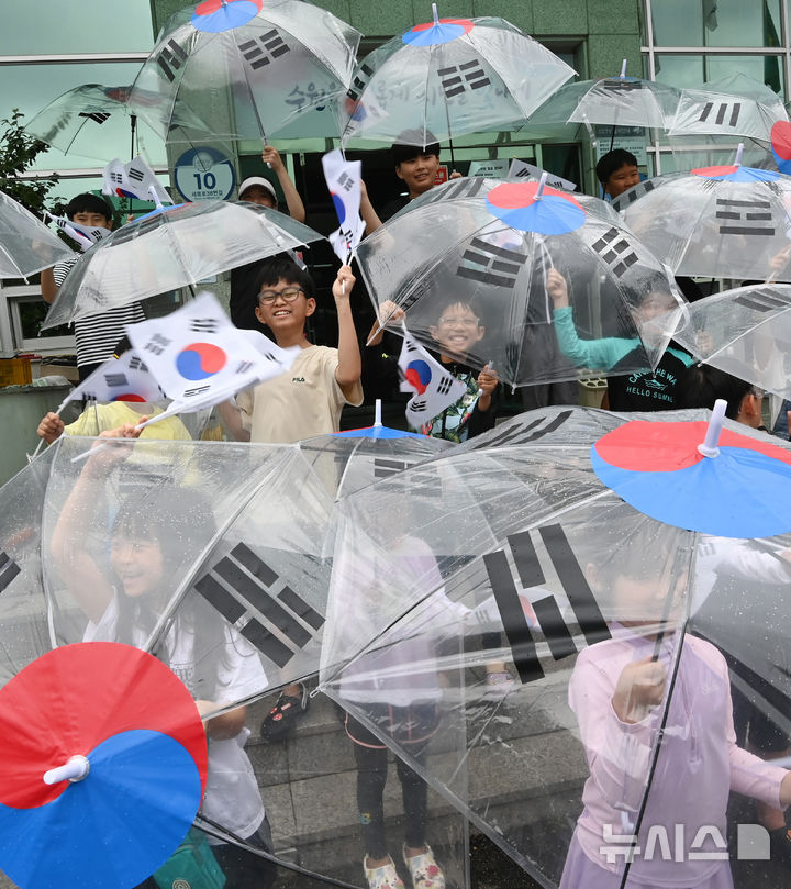 [수원=뉴시스] 김종택 기자 = 제80주년 광복절을 하루 앞둔 14일 경기 수원시 세류1동 행정복지센터에서 세류1동 새마을문고 '책먹는 아이들' 어린이들이 태극기 우산을 쓰고 만세삼창을 외치고 있다. 2025.08.14. jtk@newsis.com