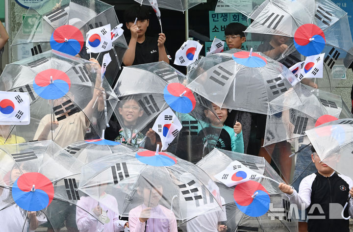 [수원=뉴시스] 김종택 기자 = 제80주년 광복절을 하루 앞둔 14일 경기 수원시 세류1동 행정복지센터에서 세류1동 새마을문고 '책먹는 아이들' 어린이들이 태극기 우산을 쓰고 만세삼창을 외치고 있다. 2025.08.14. jtk@newsis.com
