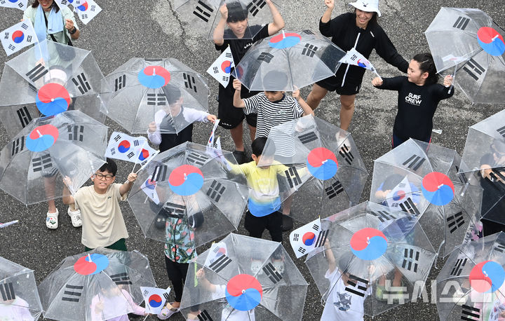 [수원=뉴시스] 김종택 기자 = 제80주년 광복절을 하루 앞둔 14일 경기 수원시 세류1동 행정복지센터에서 세류1동 새마을문고 '책먹는 아이들' 어린이들이 태극기 우산을 쓰고 만세삼창을 외치고 있다. 2025.08.14. jtk@newsis.com