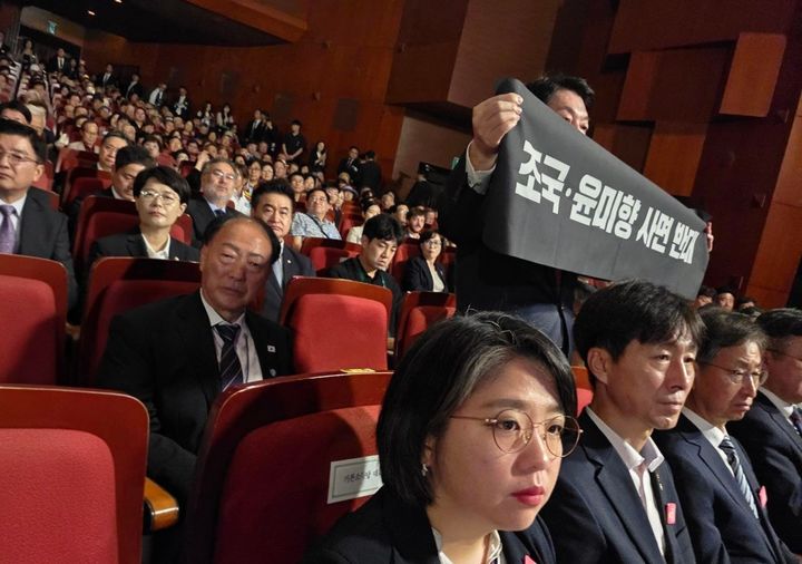 [서울=뉴시스] 안철수 국민의힘 당 대표 후보가 15일 서울 세종문화회관에서 열린 '제80주년 광복절 경축식'에서 이재명 대통령이 연설하는 동안 '조국·윤미향 사면 반대' 문구가 적힌 현수막을 들었다. (사진 = 안철수 의원실 제공) 2025.08.15 photo@newsis.com *재판매 및 DB 금지