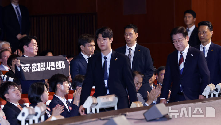 [서울=뉴시스] 최동준 기자 = 이재명 대통령이 15일 서울 종로구 세종문화회관에서 열린 제80주년 광복절 경축식에서 경축사를 마치고 이동하고 있는 가운데 안철수 국민의힘 당대표 후보가 조국, 윤미향 사면 반대 피켓을 들고 있다. 2025.08.15. photocdj@newsis.com