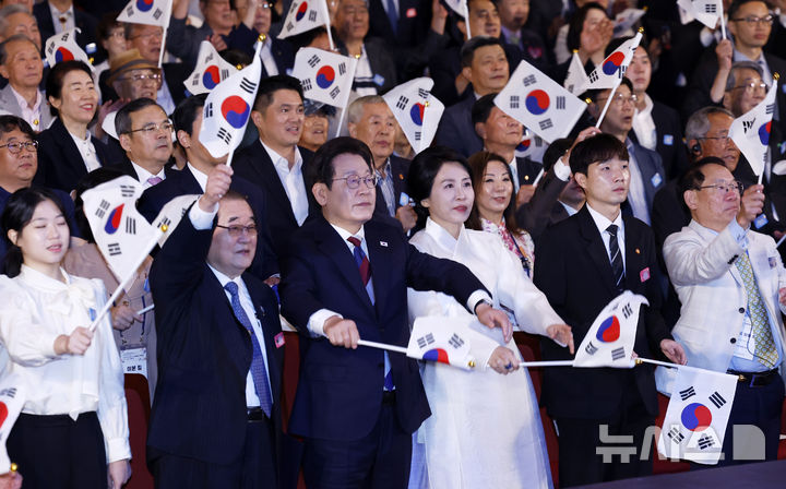 [서울=뉴시스] 최동준 기자 = 이재명 대통령과 김혜경 여사가 15일 서울 종로구 세종문화회관에서 열린 제80주년 광복절 경축식에서 참석자들과 태극기를 흔들고 있다. 2025.08.15. photocdj@newsis.com