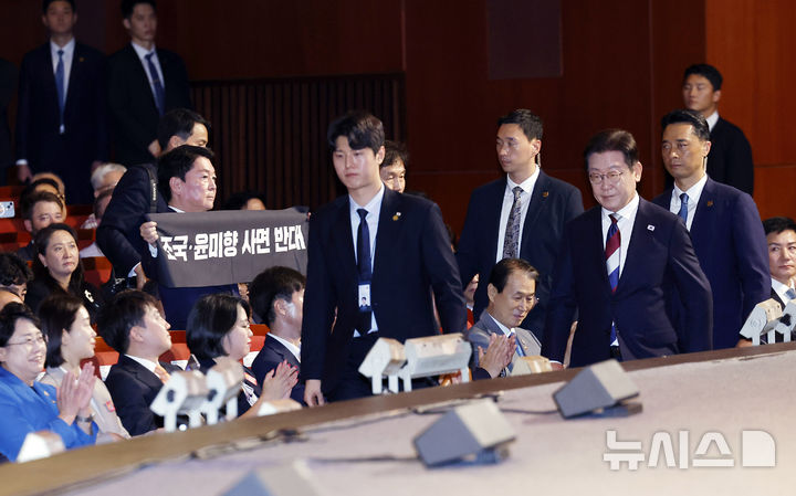 [서울=뉴시스] 최동준 기자 = 이재명 대통령이 15일 서울 종로구 세종문화회관에서 열린 제80주년 광복절 경축식에서 경축사를 마치고 이동하고 있는 가운데 안철수 국민의힘 당대표 후보가 조국, 윤미향 사면 반대 피켓을 들고 있다. 2025.08.15. photocdj@newsis.com