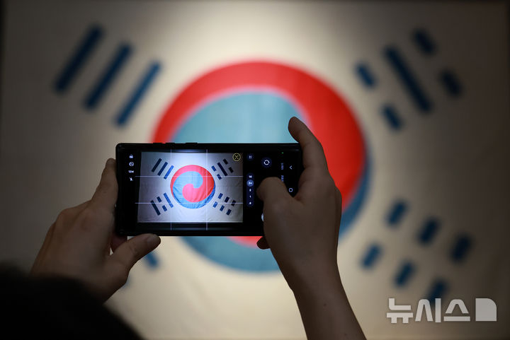 [서울=뉴시스] 이영환 기자 = 광복절인 15일 오후 서울 용산구 국립중앙박물관을 찾은 관람객들이 데니 태극기를 살펴보고 있다.  국내에 남아 있는 태극기 중 가장 오래된 데니 태극기는 고종이 외교고문이었던 미국인 데니에게 하사한 태극기다. 2025.08.15. 20hwan@newsis.com