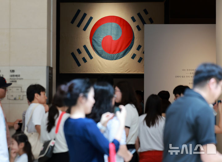 [서울=뉴시스] 이영환 기자 = 광복절인 15일 오후 서울 용산구 국립중앙박물관을 찾은 관람객들이 데니 태극기를 살펴보고 있다.  국내에 남아 있는 태극기 중 가장 오래된 데니 태극기는 고종이 외교고문이었던 미국인 데니에게 하사한 태극기다. 2025.08.15. 20hwan@newsis.com