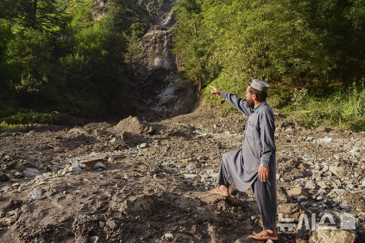 A villagers points out area as he stands over the debris of damaged houses at the incident site of cloudburst that triggered flash flood, in Naryan Behak village near Muzaffarabad, the main town of Pakistan's controlled Kashmir, Friday, Aug. 15, 2025. (AP Photo/M.D. Mughal)