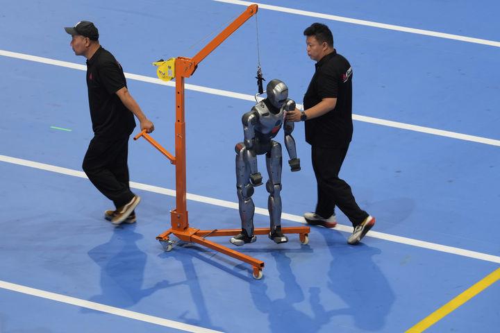 [베이징=AP/뉴시스] 14일(현지 시간) 중국 베이징 국가스피드스케이팅경기장에서 열린 2025 세계 휴머노이드 로봇 운동회 개막식에 앞서 관계자들이 로봇을 옮기고 있다. 2025.08.18.
