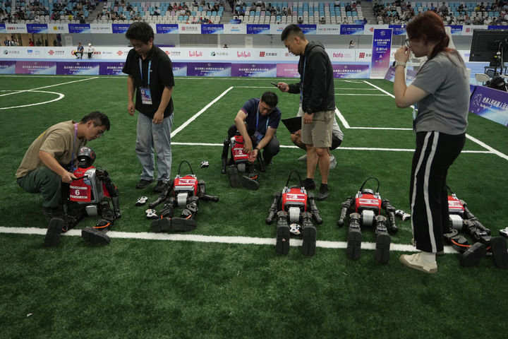 [베이징=AP/뉴시스] 15일(현지 시간) 중국 베이징 국가스피드스케이팅경기장에서 열린 2025 세계 휴머노이드 로봇 운동회에서 기술자들이 축구 경기에 앞서 로봇을 점검하고 있다. 2025.08.18.