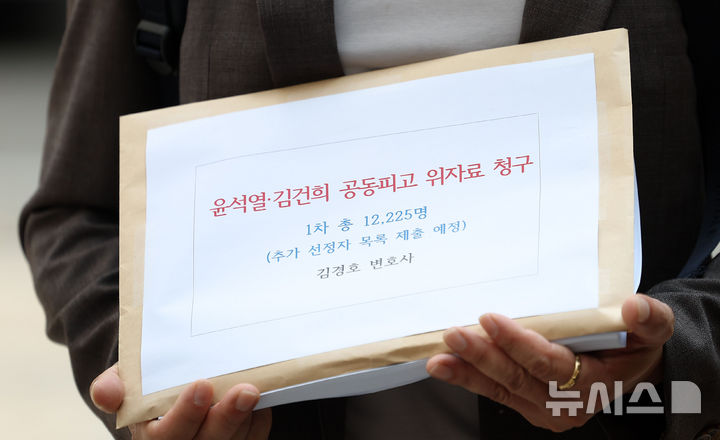 [서울=뉴시스] 김선웅 기자 = 김경호 변호사가 18일 서울 서초구 서울중앙지법에서 전직 대통령 윤석열과 부인 김건희를 상대로 1인당 10만 원의 위자료(소송 신청인 12,225명)를 청구하는 '불법 계엄 위자료' 손해배상 소송 소장 접수를 앞두고 입장을 말하는 옆에서 관계자가 청구 소장을 들고 있다. 2025.08.18. mangusta@newsis.com