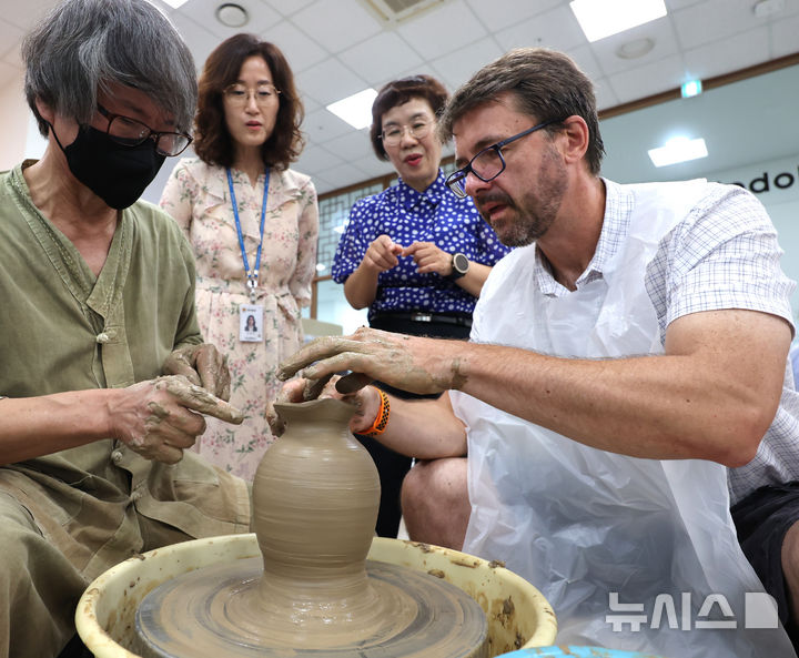 [인천=뉴시스] 전진환 기자 = 18일 오후 인천 연수구 인천경제자유구역청 글로벌센터에서 열린 녹청자 도예 강좌에 참가한 외국인이 도예 장인의 도움을 받아 도자기를 빚고 있다. 2025.08.18. amin2@newsis.com