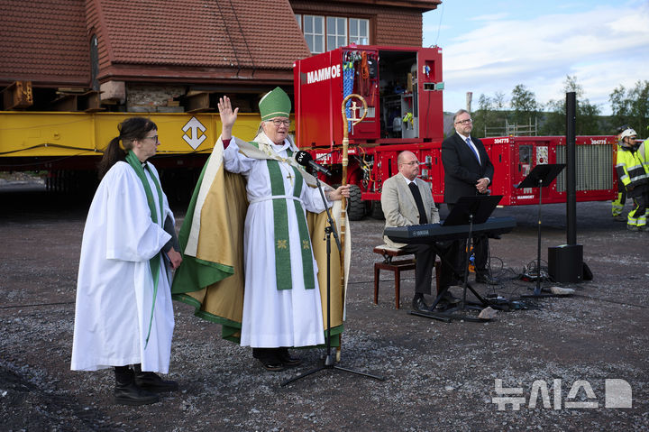 [키루나=AP/뉴시스] 레나 셰른베리 목사(왼쪽)와 아사 뉘스트롬 주교가 키루나 교회(Kiruna Kyrka, 사미 스타일의 목조 스웨덴 루터교 교회)를 축복하고 있다. 이 교회는 마을 이전 계획의 일환으로, 새로운 시내 중심지까지 동쪽으로 5km(약 3마일) 이동하기 직전이다. 2025.08.19.