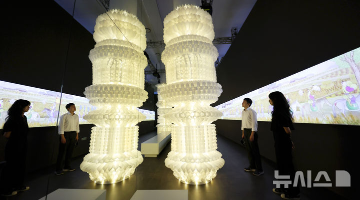 [서울=뉴시스] 홍효식 기자 = 19일 서울 중구 동대문디자인플라자(DDP)에서 열린 '헤리티지 : 더 퓨처 판타지' 전시 기자간담회에서 국가유산진흥원 직원들이 조선 왕실의 행차 풍경인 '환어행렬도' 미디어아트를 배경으로 한지를 활용한 '귀환의 메아리' 작품을 살펴보고 있다. 국내 최초 국가유산을 활용한 디지털 콘텐츠 종합 전시 '헤리티지 : 더 퓨처 판타지'는 오는 23일 개막해 9월 17일까지 열린다. 2025.08.19. yesphoto@newsis.com