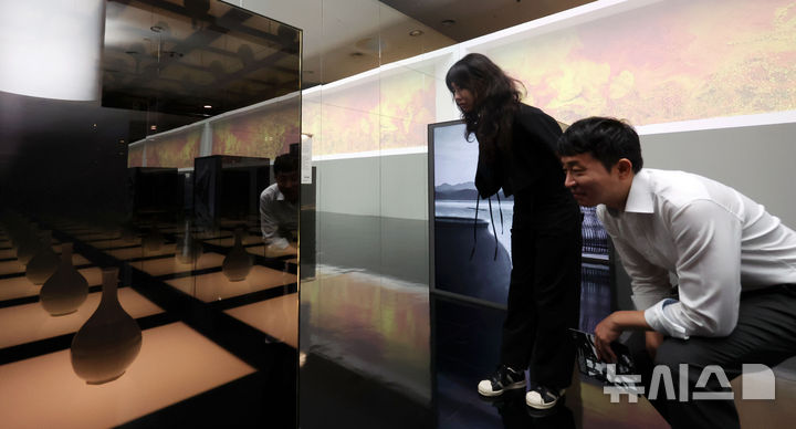 [서울=뉴시스] 홍효식 기자 = 19일 서울 중구 동대문디자인플라자(DDP)에서 열린 '헤리티지 : 더 퓨처 판타지' 전시 기자간담회에서 국가유산진흥원 직원들이 국가무형유산 장인들의 공예기술을 담은 AI 영상 '자연으로부터' 미디어아트와 실제 전승공예품을 살펴보고 있다.국내 최초 국가유산을 활용한 디지털 콘텐츠 종합 전시 '헤리티지 : 더 퓨처 판타지'는 오는 23일 개막해 9월 17일까지 열린다. 2025.08.19. yesphoto@newsis.com