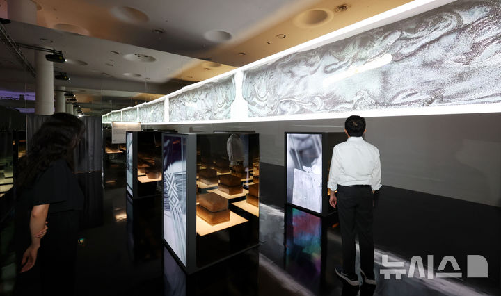 [서울=뉴시스] 홍효식 기자 = 19일 서울 중구 동대문디자인플라자(DDP)에서 열린 '헤리티지 : 더 퓨처 판타지' 전시 기자간담회에서 국가유산진흥원 직원들이 국가무형유산 장인들의 공예기술을 담은 AI 영상 '자연으로부터' 미디어아트와 실제 전승공예품을 살펴보고 있다.국내 최초 국가유산을 활용한 디지털 콘텐츠 종합 전시 '헤리티지 : 더 퓨처 판타지'는 오는 23일 개막해 9월 17일까지 열린다. 2025.08.19. yesphoto@newsis.com