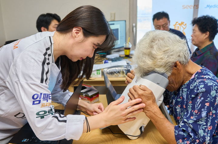 [서울=뉴시스] 대부도 주민이 AI 실명질환 진단 솔루션 ‘위스키’와 안저카메라 ‘옵티나 제네시스’를 활용해 안저 상태를 확인하고 있다. (사진=대웅제약 제공) 2025.08.20. photo@newsis.com *재판매 및 DB 금지