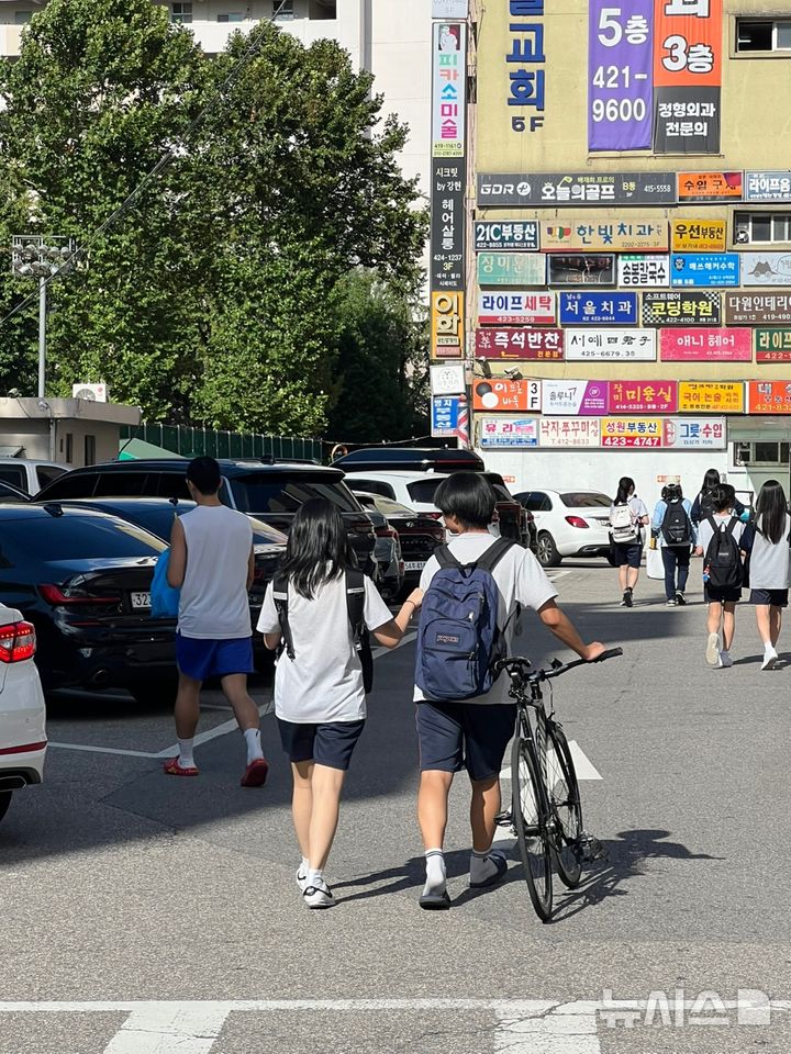 [서울=뉴시스] 김중황 인턴기자=19일 오후 서울 송파구 소재 중학교 앞에서 한 학생이 픽시 자전거를 끌고 가고 있다. 2025.08.19