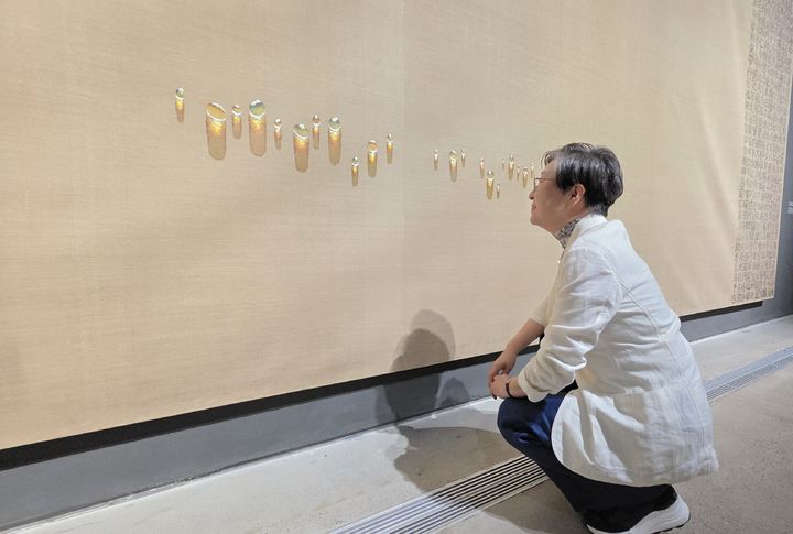 [사진=박현주 미술전문기자]김성희 관장이 김창열 회귀 대작에 아래에 그려진 물방울을 살펴보고 있다. *재판매 및 DB 금지