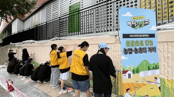 [세종=뉴시스] 농림축산식품부는 지난 23일 서울 성동구 마장동에서 '농업·농촌 가치확산 캠페인' 벽화 작업을 진행했다고 25일 밝혔다. 사진은 대학생연합 동아리 꿈꾸는 붓이 안심상가 마장청계점 벽면에 농업·농촌의 가치를 담은 벽화를 그리고 있는 모습. (사진=농식품부 제공) 2025.08.25. photo@newsis.com *재판매 및 DB 금지