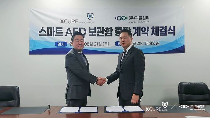 안은철 엑스큐어 대표(왼쪽)와 송은길 피플멀티 부사장(오른쪽)이 지난 21일 열린 ‘스마트 AED 보관함’ 총판 계약 체결식에서 기념 촬영을 하고 있다. (사진=엑스큐어) *재판매 및 DB 금지