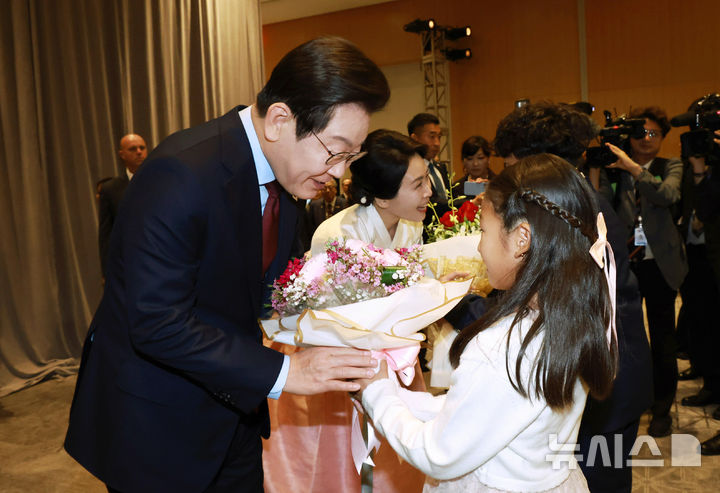 [워싱턴=뉴시스] 고범준 기자 = 이재명 대통령과 김혜경 여사가 24일(현지 시간) 미국 워싱턴DC의 한 호텔에서 열린 재미동포 만찬 간담회에서 화동에게 꽃다발을 받고 있다. 2025.08.25. bjko@newsis.com