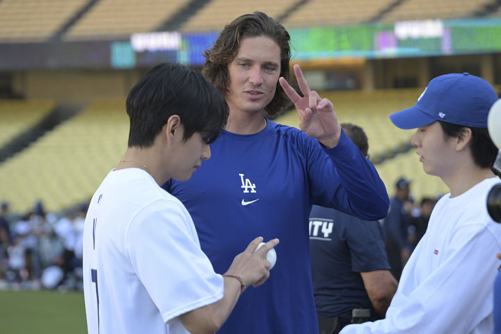 [로스앤젤레스=AP/뉴시스] 방탄소년단(BTS)의 뷔(왼쪽)가 25일(현지 시간) 미 캘리포니아주 로스앤젤레스의 다저 스타디움에서 LA 다저스 투수 타일러 글래스노와 공 쥐는 방법(그립)에 관해 얘기하고 있다. 뷔는 이날 LA 다저스와 신시내티 레즈의 경기 시구자로 나섰다. 2025.08.26.