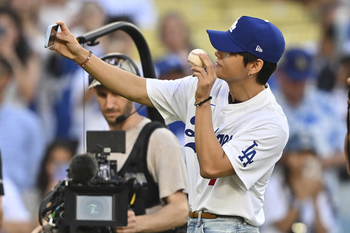 [로스앤젤레스=AP/뉴시스] 방탄소년단(BTS)의 뷔가 25일(현지 시간) 미 캘리포니아주 로스앤젤레스의 다저 스타디움에서 2025 메이저리그 LA 다저스와 신시내티 레즈와의 경기 전 시구에 앞서 공을 들고 셀카를 찍고 있다. 2025.08.26.