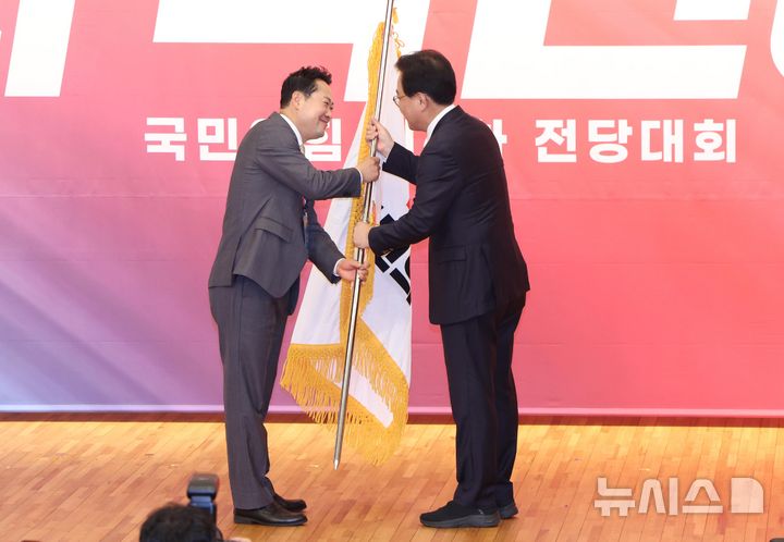 [서울=뉴시스] 국회사진기자단 = 장동혁 신임 국민의힘 대표가 26일 서울 여의도 국회도서관에서 열린 국민의힘 제6차 전당대회 결선에서 송언석 비상대책위원장 겸 원내대표로부터 당기를 전달 받고 있다. 2025.08.26. photo@newsis.com