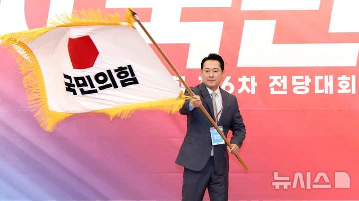 [서울=뉴시스] 국회사진기자단 = 장동혁 신임 국민의힘 대표가 26일 서울 여의도 국회도서관에서 열린 국민의힘 제6차 전당대회 결선에서 당기를 흔들고 있다. 2025.08.26. photo@newsis.com