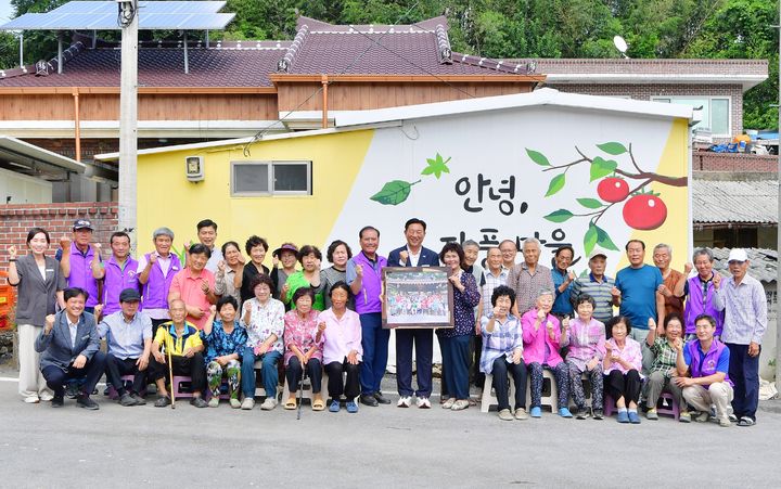 [장성=뉴시스] 전남 장성군이 고향사랑기금으로 추진하는 '고향마을 공동체 활성화사업'을 통해 단체 사진을 제작한 남면 자풍마을 주민들이 김한종 장성군수와 전달식을 열고 있다. (사진 = 장성군 제공) 2025.08.27. photo@newsis.com *재판매 및 DB 금지