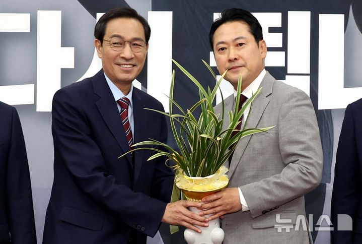 [서울=뉴시스] 조성봉 기자 = 장동혁 국민의힘 대표가 27일 오후 서울 여의도 국회에서 우상호 대통령비서실 정무수석에게 이재명 대통령 명의의 축하 난을 선물받고 기념촬영을 하고 있다. 2025.08.27. suncho21@newsis.com