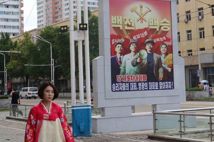 [평양=AP/뉴시스] 28일 북한 평양 시내 도로에서 한복을 입은 여성이 '제9차 당 대회' 포스터 옆을 지나고 있다. 2025.08.28.