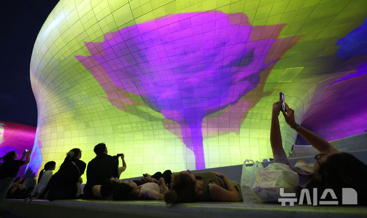 [서울=뉴시스] 조성우 기자 = 28일 오후 서울 중구 동대문디자인플라자(DDP)에서 열린 '서울라이트 DDP 2025 가을'을 찾은 시민들과 외국인 관광객들이 미디어파사드 작품을 관람하고 있다. 2025.08.28. xconfind@newsis.com