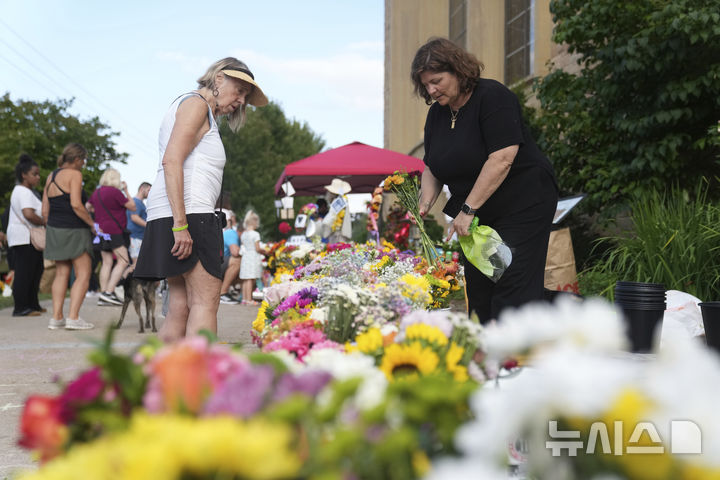 [미니애폴리스=AP/뉴시스] 28일(현지 시간) 미국 미네소타주 미니애폴리스의 가톨릭 학교 성당 앞에서 추모객들이 총격 사건으로 숨진 희생자들을 추모하고 있다. 2025.08.29.