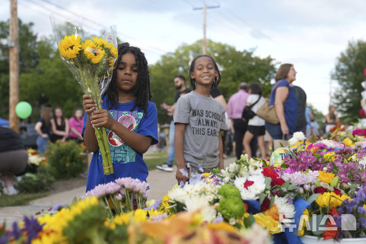 [미니애폴리스=AP/뉴시스] 28일(현지 시간) 미국 미네소타주 미니애폴리스의 가톨릭 학교 성당 앞에서 추모객들이 총격 사건으로 숨진 희생자들을 추모하고 있다. 2025.08.29.