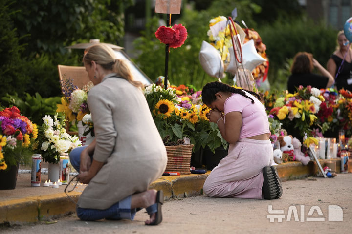 [미니애폴리스=AP/뉴시스] 28일(현지 시간) 미국 미네소타주 미니애폴리스의 가톨릭 학교 성당 앞에서 추모객들이 총격 사건으로 숨진 희생자들을 추모하고 있다. 2025.08.29.