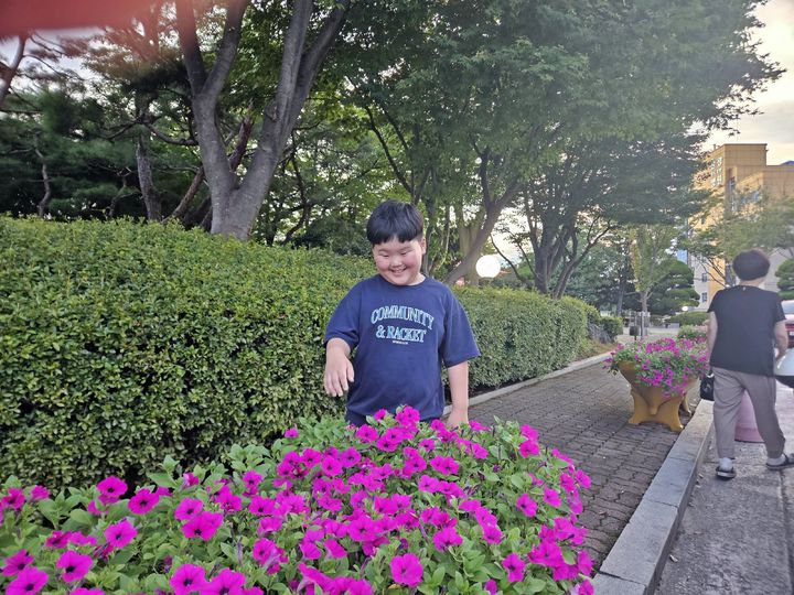 군산시청 광장에 마련된 화분에서 활짝 핀 나팔 모양의 꽃을 한 어린이가 환한 표정으로 바라보고 있다. *재판매 및 DB 금지