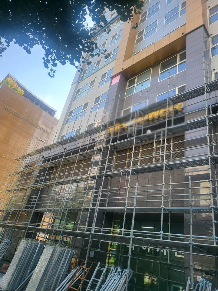 [창원=뉴시스] 지난 23일 오후 경남 창원시 상남동의 한 오피스텔 건물 외벽에서 대리석이 추락해 보행자 통행이 제한되고 있다. 건물 상단에 분홍색 사각형 부분이 대리석이 떨어진 위치. (사진=독자 제공) 2025.08.29. photo@newsis.com *재판매 및 DB 금지