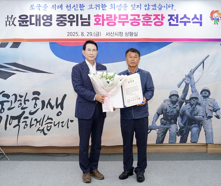 [서산=뉴시스] 6.25 참전유공자 고(故) 윤대영 중위 조카사위 고기영(오른쪽)씨가 29일 서산시청 시장실에서 이완섭 시장에게 윤 중위의 화랑무공훈장증을 대신 받은 뒤 기념 사진을 찍고 있다. (사진=서산시 제공) 2025.08.29. photo@newsis.com *재판매 및 DB 금지
